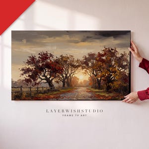 Può includere: Un dipinto paesaggistico rettangolare che raffigura una scena autunnale con alberi dal fogliame rosso e arancione lungo un sentiero. Una staccionata in legno corre lungo il lato sinistro e il sole è visibile all'orizzonte. Il testo LAYERWISHSTUDIO FRAME TV ART è stampato sotto.