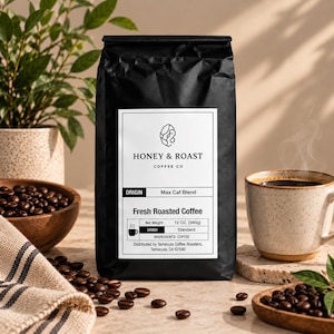 Könnte beinhalten: Eine schwarze Kaffeetüte mit einem weißen Etikett mit der Aufschrift Honey & Roast Coffee Co, Max Caf Blend und Fresh Roasted Coffee. Das Etikett gibt ein Nettogewicht von 340g und einen Standard-Mahlgrad an. Die Tüte ist von Kaffeebohnen umgeben.
