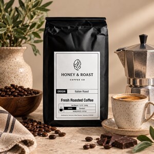 Op de afbeelding: Een zwarte zak Honey & Roast Coffee Co. Italian Roast koffie met een wit etiket. Het etiket toont de tekst Honey & Roast Coffee Co., Origin Italian Roast, Fresh Roasted Coffee en Net Weight 340g (12 oz.).