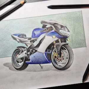 Pode incluir: Um desenho a lápis de cor sobre papel branco representando uma motocicleta esportiva azul e branca. A motocicleta é mostrada de perfil, apresentando um para-brisa escuro, um freio a disco dianteiro e um descanso lateral. Lápis de cor cercam o papel.