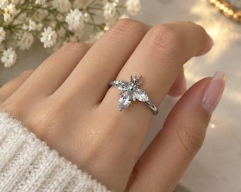 May include: A silver-toned ring featuring a bee-shaped design adorned with clear, marquise-cut crystals. The insect motif is centered on a thin, polished metal band, with the wings and body of the bee formed by the arrangement of the faceted stones.
