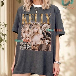 Könnte beinhalten: Ein anthrazitfarbenes Kurzarm-T-Shirt mit einem großen Grafikdruck der Schauspielerin Kelly Reilly. Das Design zeigt den Namen KELLY REILLY in goldener Schrift über einer Collage aus vier verschiedenen Fotos der Schauspielerin.