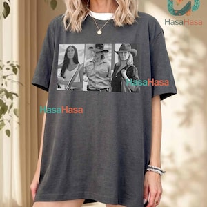Könnte beinhalten: Ein anthrazitfarbenes Kurzarm-T-Shirt mit einem rechteckigen schwarz-weißen Grafikdruck von drei Personen in Western-Kleidung. Das T-Shirt hat einen Rundhalsausschnitt und eine lockere Passform. Der Text COMFORT COLORS - PEPPER ist sichtbar.