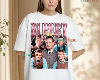 May include: A white t-shirt featuring a graphic print of the character Rupert Giles from Buffy the Vampire Slayer. The design includes the text RUPERT GILES in a metallic pink font, surrounded by multiple images of the character in various outfits.
