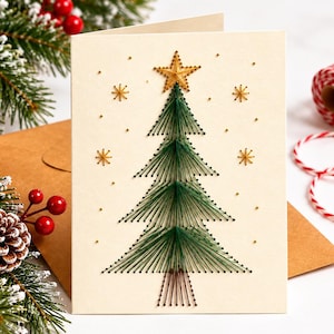 Puede incluir: Una tarjeta de felicitación de color crema con un diseño de arte con hilos que representa un árbol de Navidad en hilo verde oscuro con una estrella dorada en la parte superior. El árbol está rodeado de pequeñas estrellas doradas y puntos.