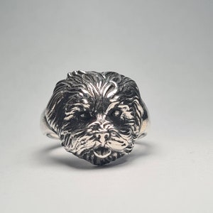 May include: A silver ring with a detailed dog's head design. The ring showcases the dog's fur texture and facial features. This statement ring is ideal for those who appreciate unique jewellery and have a fondness for dogs.