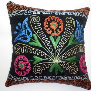 May include: Black velvet pillow with colorful embroidered flowers. The flowers are in shades of blue, green, orange, pink, and gold.