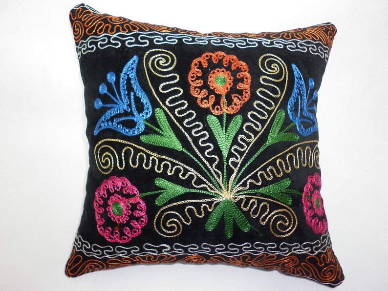 May include: Black velvet pillow with colorful embroidered flowers. The flowers are in shades of blue, green, orange, pink, and gold.