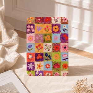 May include: A rectangular tablet case featuring a grid pattern of hand-painted squares, each containing a unique floral illustration in vibrant colours including red, yellow, orange, pink, purple, blue, and green against varied background hues.