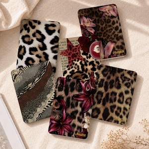 May include: A collection of five rectangular cases featuring various animal print patterns including leopard and zebra designs. Some cases display floral accents, a red billiard ball with the number seven, and the names Victoria, Jessica, and Evelyn.