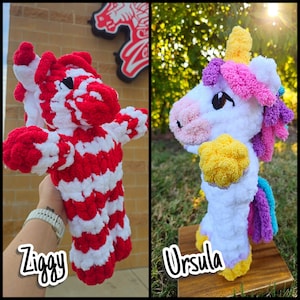 May include: Two plush toys made of thick yarn. On the left, Ziggy is a zebra-patterned toy with alternating red and white stripes. On the right, Ursula is a white unicorn with a yellow horn, a pink and purple mane, and a blue tail.