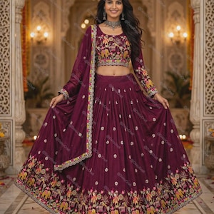 May include: A deep plum-coloured lehenga choli set featuring a cropped blouse and a floor-length pleated skirt. Both pieces are adorned with intricate multi-coloured embroidery depicting elephants and floral motifs, complemented by a matching dupatta.