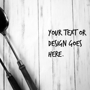 May include: Black and white image of a spoon and fork with wooden handles. The text "YOUR TEXT OR DESIGN GOES HERE" is written in a handwritten style. The background is a white wooden surface.