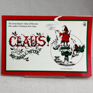 Può includere: Una copertina di libro rettangolare con bordo rosso e il titolo CLAUS! di Michael C. Witte. La copertina mostra un'illustrazione in bianco e nero di un elfo che rade una figura barbuta su una sedia, con agrifoglio e il testo A CLAUS SHAVE.