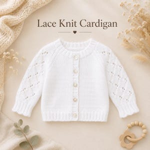 May include: A white long-sleeve knit cardigan featuring a delicate lace pattern on the sleeves, a ribbed crew neckline, and five small buttons down the front. The text "Lace Knit Cardigan" is printed above the garment in a dark brown font.