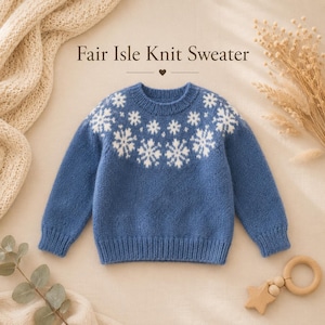 Peut inclure: Un pull en tricot bleu avec un motif de flocons de neige blancs autour de l'empiècement, un col rond, ainsi que des poignets et un ourlet côtelés. Le texte Fair Isle Knit Sweater est imprimé au-dessus avec une petite icône de cœur.