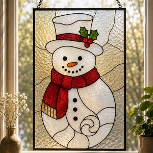 May include: A rectangular stained glass window hanging featuring a snowman with a white top hat, a red scarf, and a carrot nose. The snowman is accented with green holly leaves and red berries. The background consists of textured clear glass.