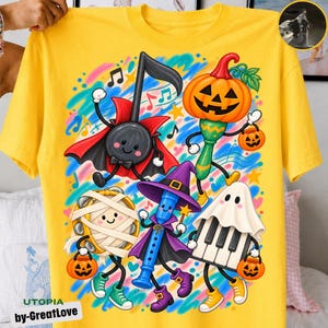 Puede incluir: Una camiseta de color amarillo brillante con un gráfico colorido de instrumentos musicales antropomórficos disfrazados de Halloween, incluyendo una maraca de calabaza, un piano fantasma, una pandereta momia, una flauta bruja y una nota musical vampiro.