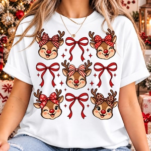 Peut inclure: Un t-shirt blanc à manches courtes orné d'un motif répétitif de quatre visages de rennes au nez rouge avec divers nœuds à motifs, entremêlés de nœuds en ruban rouge et de petites étoiles à quatre branches sur le devant du vêtement.