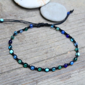 May include: A black cord anklet with blue, green, and turquoise glass beads.