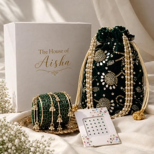 May include: A white gift box labeled The House of Aisha, a dark green velvet drawstring pouch with gold embroidery and pearl bead strands, a set of green bangles with gold accents, and a small card containing green adhesive face gems.