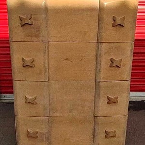 May include: A light brown wooden dresser with four drawers. Each drawer has a decorative butterfly design on the front.