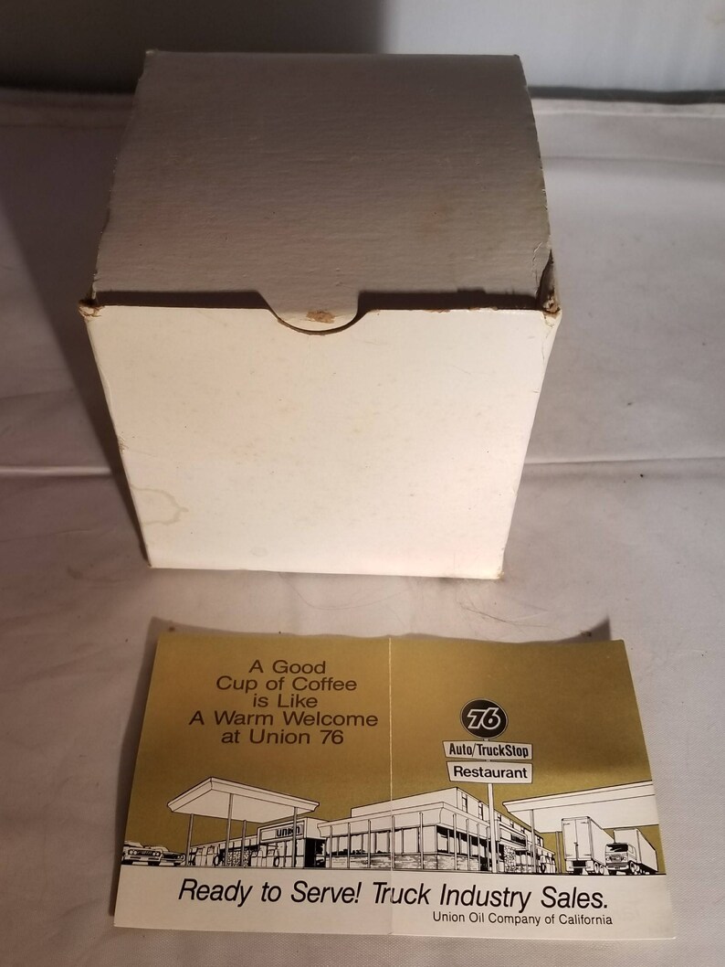May include: A white box with a gold and white label that reads "A Good Cup of Coffee is Like A Warm Welcome at Union 76". The label also features a drawing of a gas station with the text "76 Auto/TruckStop Restaurant" and "Ready to Serve! Truck Industry Sales. Union Oil Company of California".