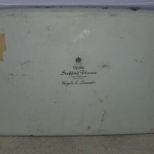 May include: A white ceramic serving tray with a black and white logo that reads "Spode Stafford Flowers Designed in England  Wisteria & Lavender".