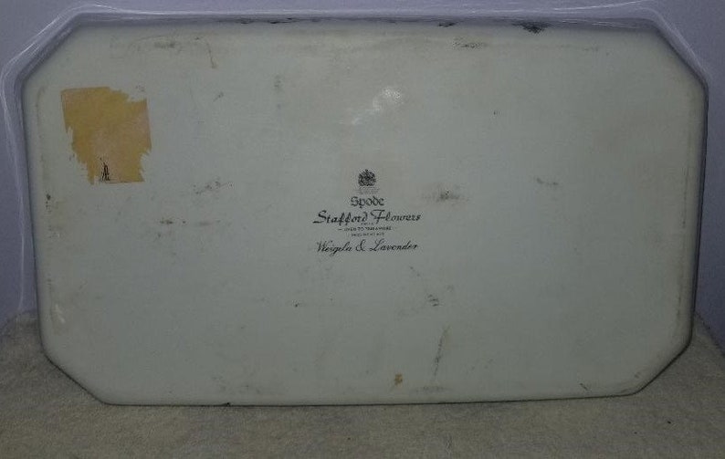May include: A white ceramic serving tray with a black and white logo that reads "Spode Stafford Flowers Designed in England  Wisteria & Lavender".