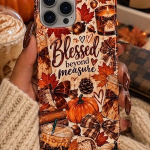 May include: A phone case featuring an autumn-themed collage with orange pumpkins, red maple leaves, pinecones, acorns, plaid bows, a lit candle, and a coffee cup. The text Blessed beyond measure is printed in the center in a dark brown script.