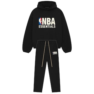 May include: A black hooded sweatshirt and matching sweatpants set. The hoodie features the NBA logo in red, white, and blue with the text NBA ESSENTIALS in white. The sweatpants include a smaller NBA ESSENTIALS logo and long beige drawstrings.
