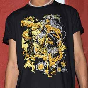 Peut inclure: Un t-shirt noir à manches courtes avec une illustration graphique en jaune, gris et blanc. Le motif représente un chevalier en armure tenant une épée, accompagné d'une silhouette portant un masque de crâne cornu, entouré de nuages et de flammes.