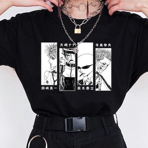 May include: A black short-sleeved t-shirt featuring a central white rectangular graphic print containing four distinct manga-style character panels with Japanese text characters above and below the illustrations, paired with black shorts and a belt.