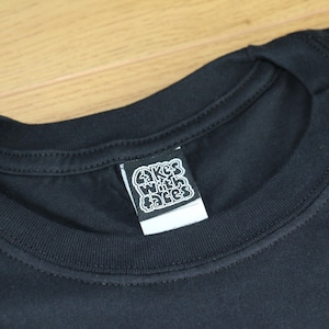 May include: Black t-shirt with a white label that says "Cakes With Faces" on it.