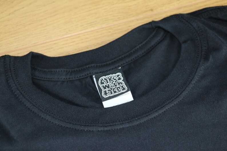 May include: Black t-shirt with a white label that says "Cakes With Faces" on it.