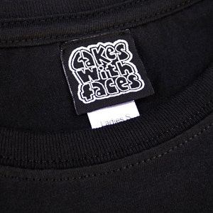 May include: Black t-shirt with a white tag that says "Cakes With Faces" and "Ladies S".