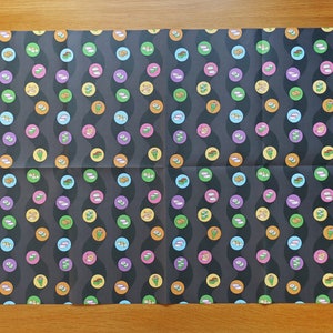 May include: A sheet of black wrapping paper with a repeating pattern of colourful sushi rolls. The sushi rolls are arranged in a wavy pattern.