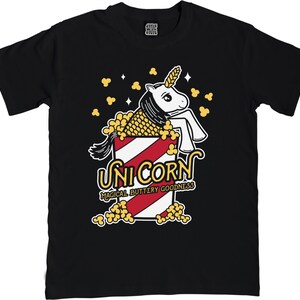 May include: Black t-shirt with a white unicorn in a red and white striped popcorn bucket. The unicorn is surrounded by yellow popcorn and the text "Unicorn Magical Buttery Goodness" is below the bucket.