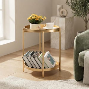 May include: A round two-tier side table with a gold metal frame and two circular trays. The top tray holds a white pot with yellow flowers and a white teacup on a saucer. The bottom tray contains a row of books standing upright in a neat arrangement.