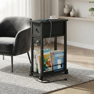 May include: A black rectangular side table with a top surface, a fabric drawer, and a lower shelf for magazines. The table features a built-in power outlet with a white charging cable plugged in. It stands on four small wheels and has a metal frame.