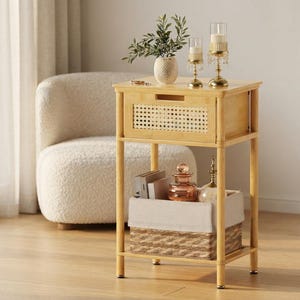 May include: A light-colored wooden side table featuring a single drawer with a woven cane front panel. The table has four legs and an open lower shelf containing a rectangular storage basket with a beige fabric liner and two glass items.