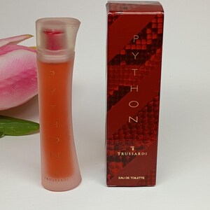 May include: A tall, slender, frosted glass perfume bottle with orange liquid and the text "PYTHON TRUSSARDI" alongside its matching rectangular box, which features a dark red snakeskin pattern and the text "PYTHON TRUSSARDI EAU DE TOILETTE".