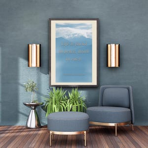 Può includere: Una stampa artistica da parete incorniciata raffigurante un paesaggio montano blu con il testo Life is found in peace, death in envy, Proverbs 14:30 inscritto al centro. La stampa è esposta in una cornice scura su una parete blu con due applique dorate.