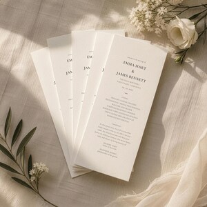 Könnte beinhalten: Ein Stapel cremefarbener Hochzeitskarten mit schwarzem Serifentext. Der Text lautet: Welcome to the marriage of Emma Hart & James Bennett, The Villa Monterra, Napa Valley, California, 05.24.2025, ceremony, remembrance, Michael Hart, Josephine Bennet.