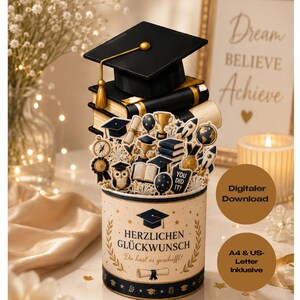 May include: A graduation-themed paper craft featuring a black mortarboard cap atop a stack of books. The base is a cylindrical container decorated with gold laurel leaves, a diploma icon, and the German text HERZLICHEN GLÜCKWUNSCH Du hast es geschafft!