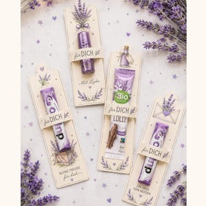 May include: Four rectangular paper cards featuring lavender illustrations and German text, each holding a small candy or chocolate item. The cards display phrases like 'für DICH', 'Mit Liebe', and 'EIN GRUB VON HERZEN' alongside purple floral motifs.