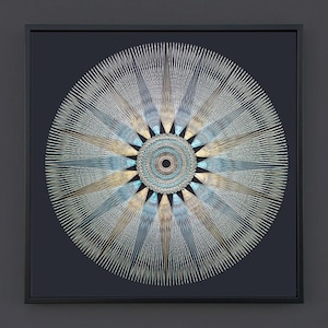 May include: A square framed wall art piece featuring a circular mandala design composed of radiating metallic silver, gold, and light blue threads. The intricate pattern creates a starburst effect against a solid dark charcoal background.