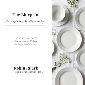 May include: A collection of white ceramic plates and bowls arranged on a white textured fabric, accompanied by small white flowers. The text reads: The Blueprint, Elevating Everyday Entertaining, The greatest luxury isn't what you spend. It's how you make people feel. Robin Ruark, Hospitality & Lifestyle Curator.
