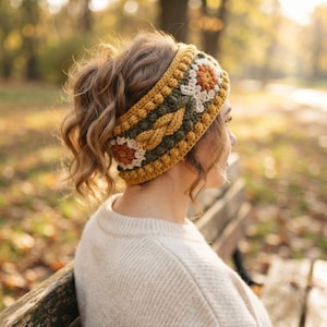 May include: A wide crochet headband featuring a textured pattern with a central cable knit design, flanked by rows of bobble stitches. The accessory displays a color palette of mustard yellow, forest green, and cream, with floral motifs.