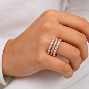 Puede incluir: Un conjunto de tres anillos de oro rosa llevados juntos en un dedo. Los anillos presentan una combinación de piedras de talla brillante redonda y piedras de talla baguette engastadas en un diseño de banda continua.